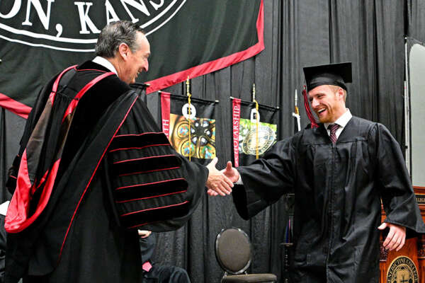 A graduate shakes hands with President Stephen Minnis during Commencement