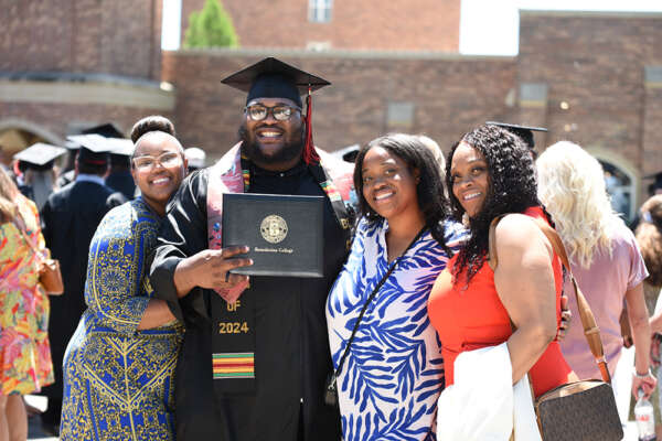 A graduate poses for a celebration photo with his family after Commencement