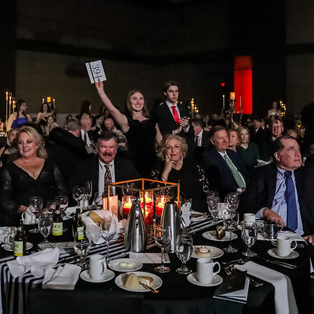 A student hostess raises a bid card for a donor at the Scholarship Ball