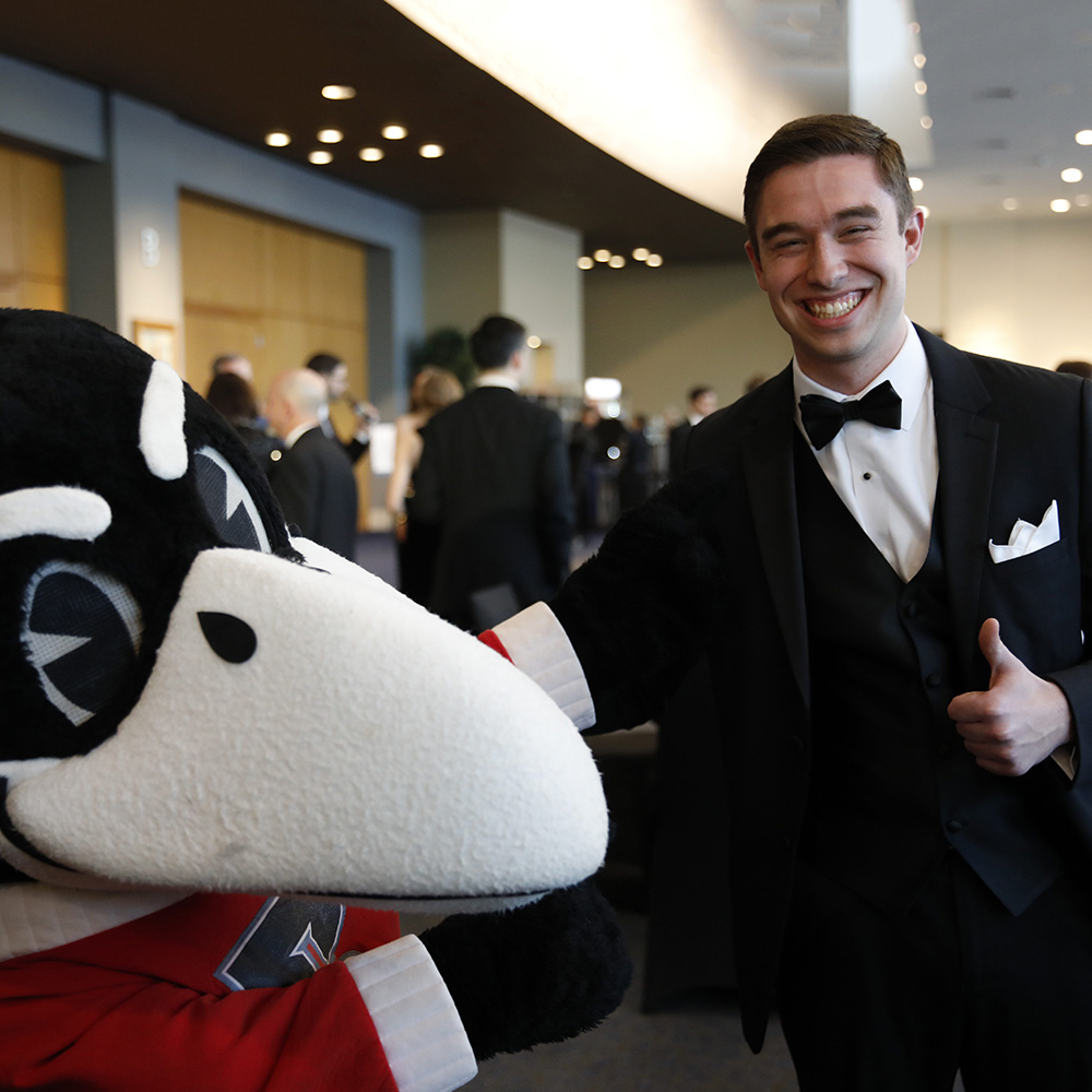 Scholarship Ball student speaker Jeff Schremmer poses with Rocky the Raven