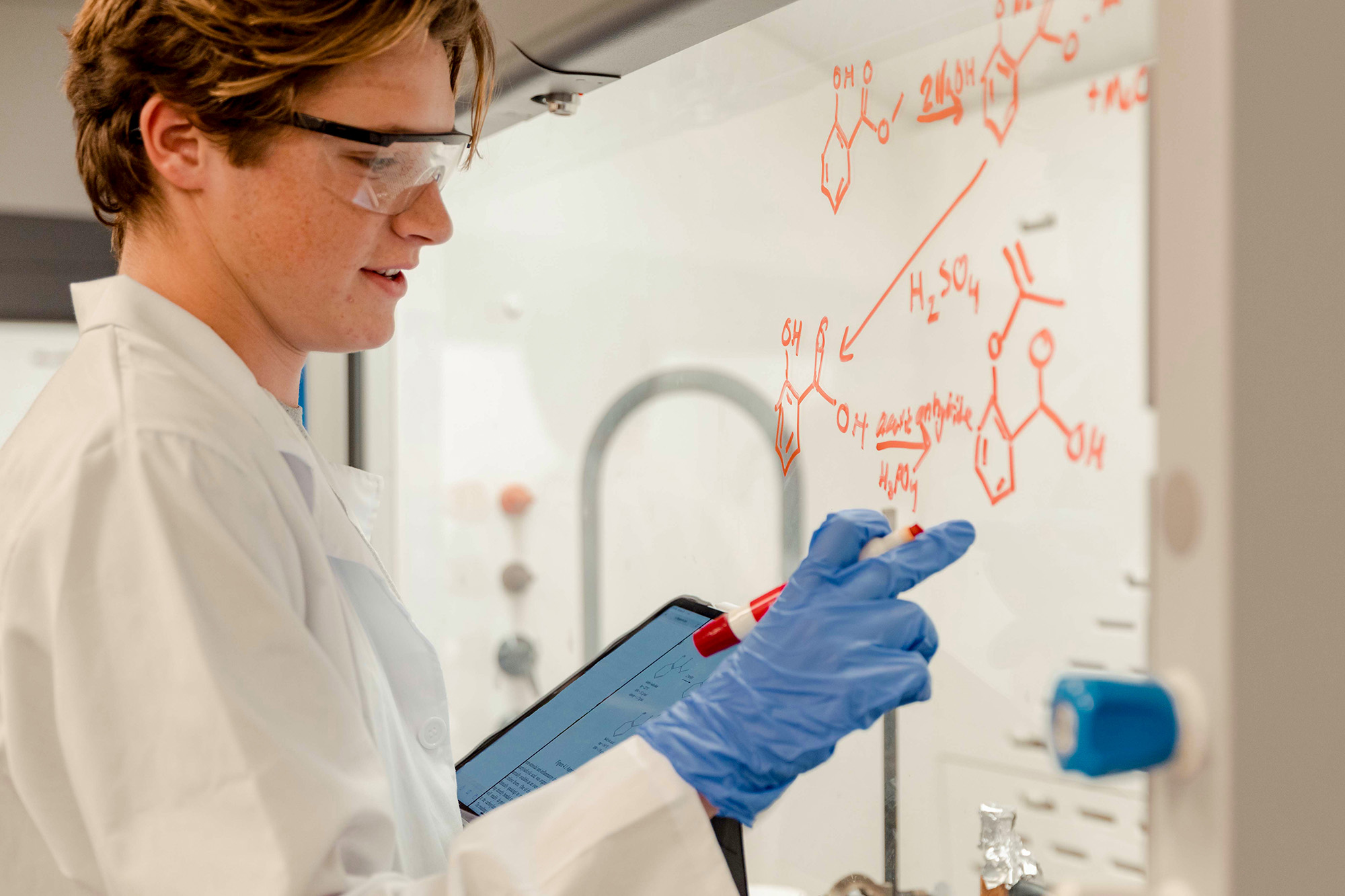 A student draws chemical diagrams on glass in a lab