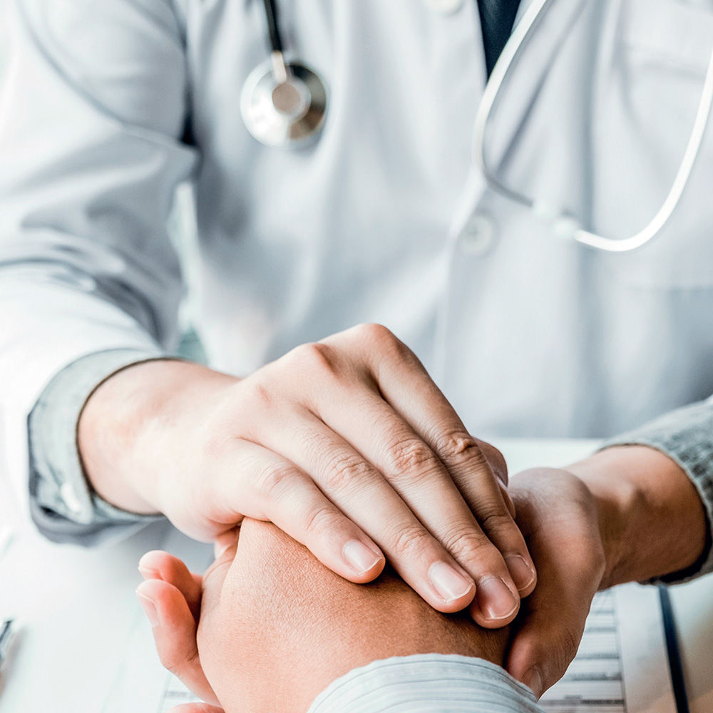 A doctor holding a patient's hand in both hands