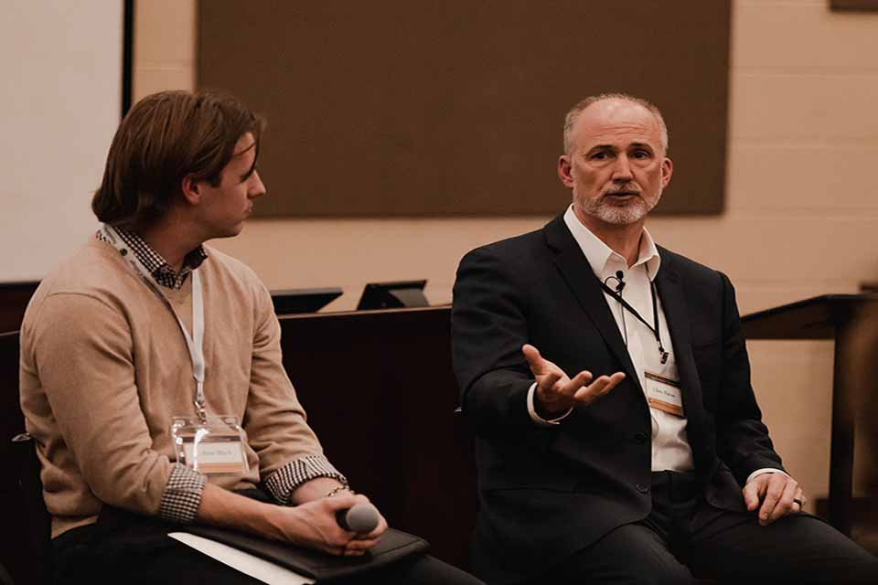 A presenter gestures to the audience 